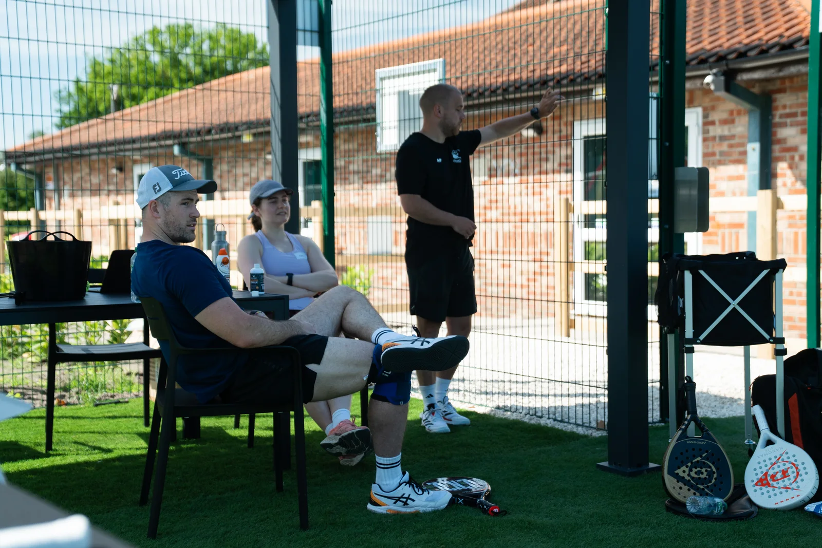 Players relaxing beside the court with rackets nearby