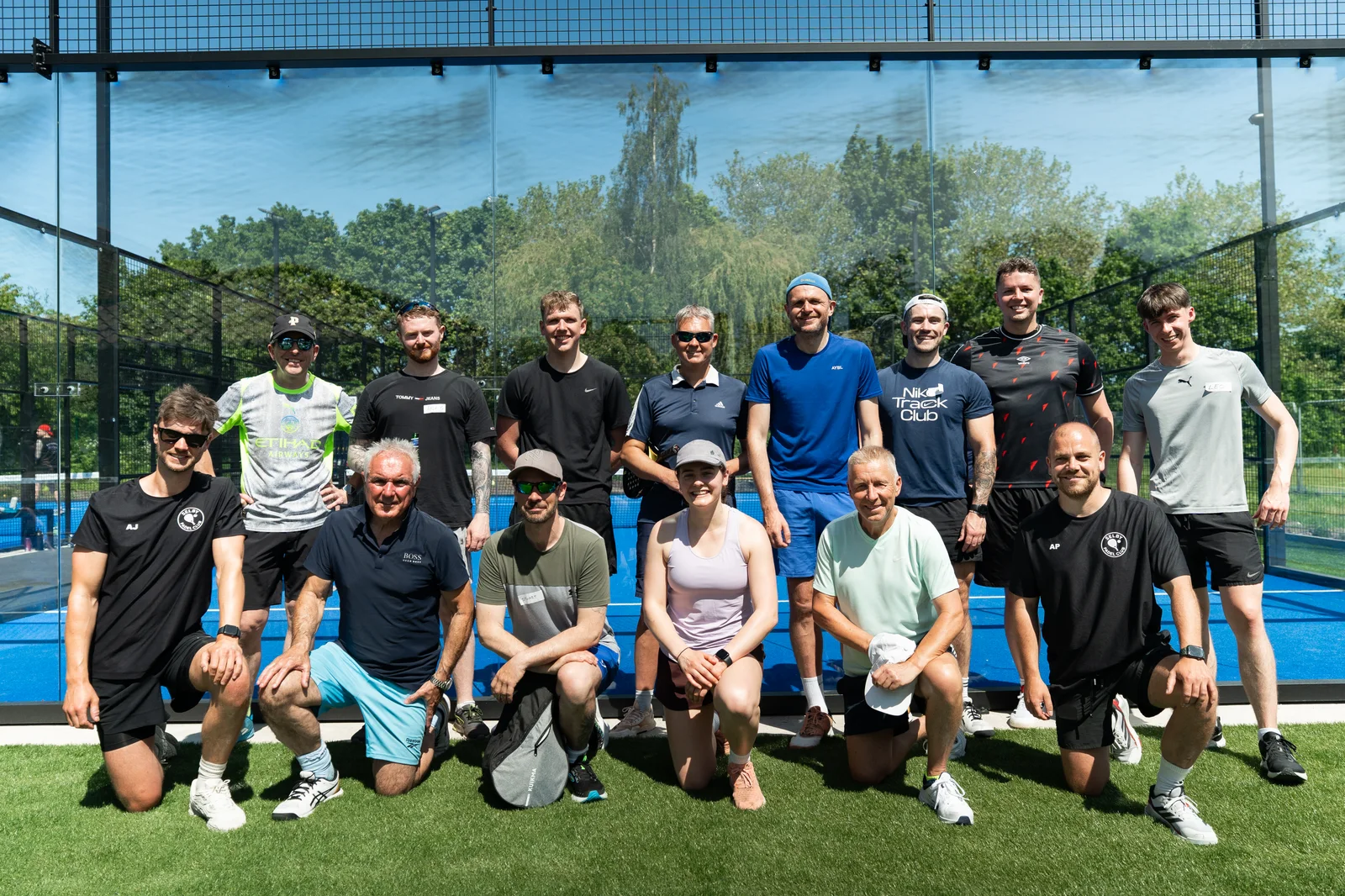 A group of players posing beside the blue courts at Selby Padel Club