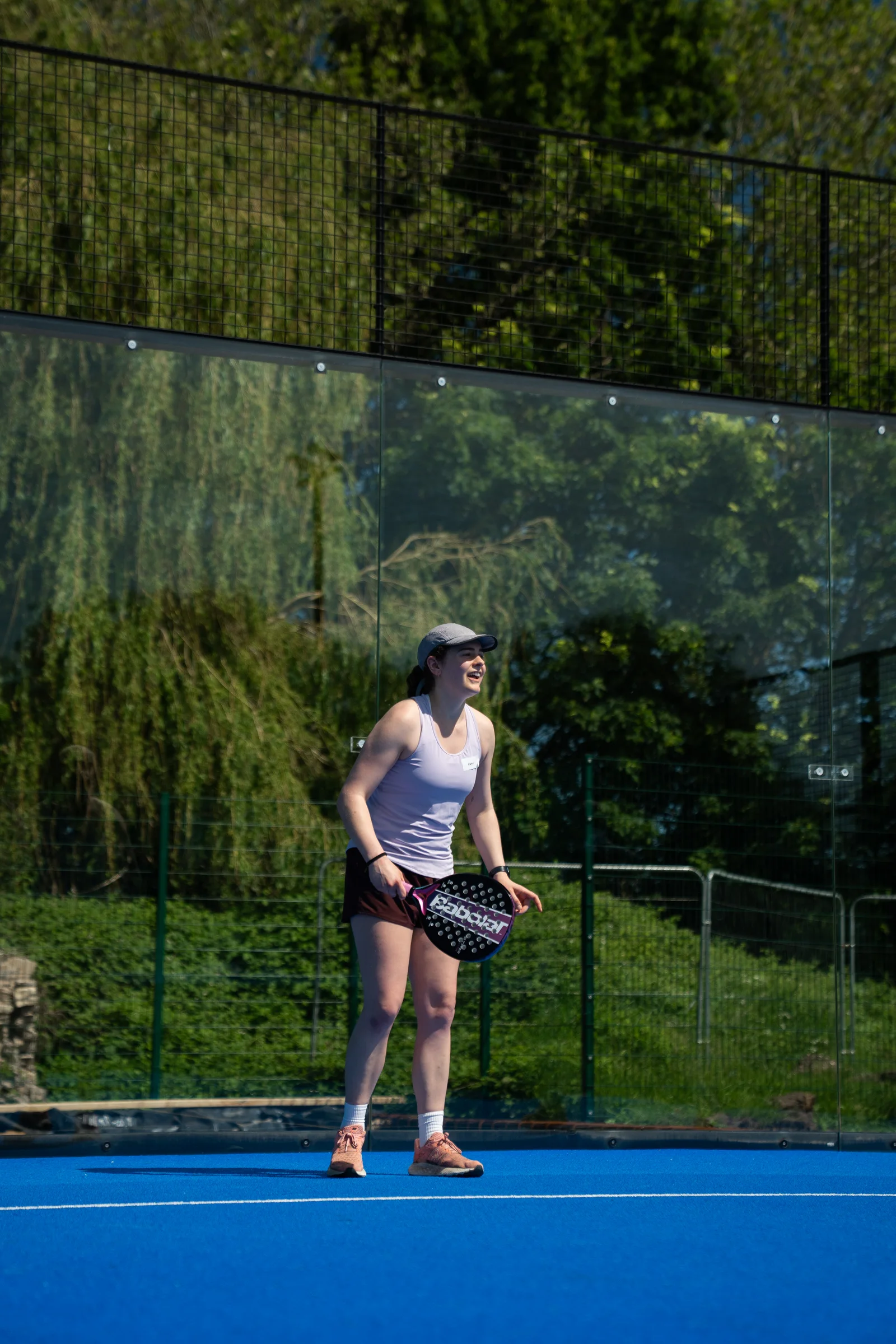 A player smiling while holding a padel racket on court