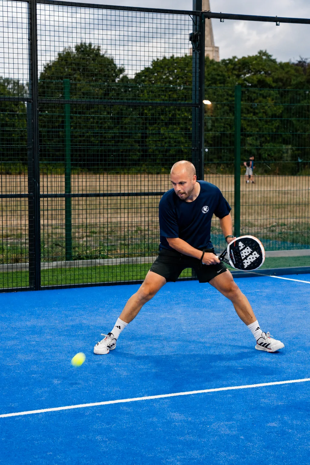 A player preparing to return a ball on the blue court